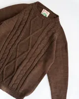 Sweater marrón de lana merino uruguaya con cuello redondo y diseño trenzado en el frente.