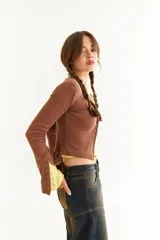 Top de manga larga color amarillo, confeccionado en tejido acanalado con cierre frontal de botones a presión metálicos. Presenta detalles de botones en los puños y un corte ajustado al cuerpo.