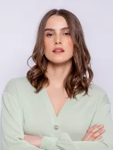 Cárdigan corto color beige, de manga larga y escote en V. Tiene cuatro botones brillantes.