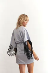 Vestido corto celeste de satén con escote en V, mangas cortas con flecos negros y drapeado en la falda.