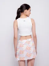 Minifalda estampada con flores en tonos celeste, azul, rosa y amarillo, con volados en el frente y cierre invisible en la parte trasera.