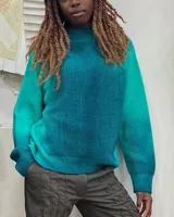 Buzo de tejido de punto en lana merino, con diseño oversize, manga ranglan y cuello levemente elevado. Presenta una textura de punto grueso y se destaca por sus colores vibrantes.