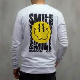Buzo blanco de algodón con cuello redondo y mangas largas. Estampado en el pecho con una cara sonriente amarilla y texto negro "SMILE" y "DUXON CO.".