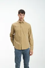 Camisa de hombre de manga larga confeccionada en pana color beige, con cuello clásico, cierre frontal con botones y bolsillo de parche en el pecho. Calce clásico.