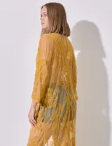 Kaftan largo color amarillo mostaza, de micro tul bordado con motivos florales. Tiene mangas largas y cordón ajustable en la cintura.