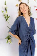 Vestido azul denim con escote en V, mangas cortas y detalle de nudo en la cintura.