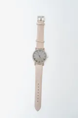 Reloj analógico con correa de cuero sintético color rosado pálido y caja a juego. La esfera es beige claro con números romanos en negro.
