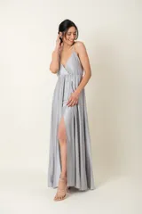 Vestido largo de satén color gris plateado, con breteles finos, escote cruzado y corte debajo del busto.