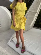 Vestido corto blanco de lino con corte evasé, mangas cortas con volados y cinto del mismo material.