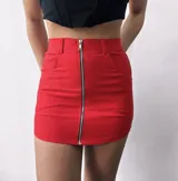 Minifalda roja de corte ajustado, con bolsillos delanteros y cierre metálico frontal.