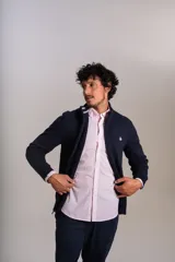 Cardigan de punto color azul marino, con cuello alto, cierre frontal completo y puños acanalados. Presenta el logo de la marca bordado en el pecho.