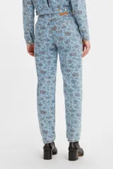 Pantalón de jean estilo mom, de tiro alto, con estampado floral en tonos azules y rosados sobre base celeste.