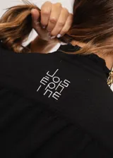 Camisa negra de cuello redondo con frunces y mangas largas con puños abiertos.