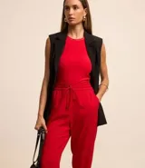 Pantalón de vestir femenino color marrón oscuro, de corte fluido y tiro medio/alto, con cintura elástica ajustable mediante cordón. Presenta bolsillos laterales y cierre frontal.