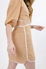 Vestido corto color lila con vivos verdes, escote en V, mangas cortas abullonadas y abertura en la cintura con detalle de argolla.