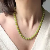Collar de cuentas esféricas de piedra en tonos verde lima, intercaladas con pequeñas cuentas turquesas y cierre metálico dorado con mosquetón.