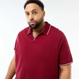 Remera de piqué color bordó, con cuello polo sin botones y detalles de líneas blancas en el borde del cuello y las mangas.