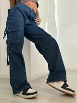 Pantalón de jean azul oscuro, de tiro bajo y corte ancho, con bolsillos cargo laterales y lazos ajustables.