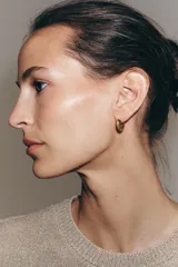 Pack de cuatro pendientes metálicos dorados. Incluye un par de aros pequeños con relieve y un par de pendientes tipo tachuela con forma alargada y aplicación de cristal central.