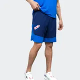 Short deportivo Umbro del Club Nacional de Football, modelo Oryn, color azul marino con paneles laterales en azul más claro y el escudo del club en el muslo izquierdo.