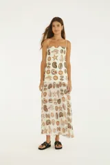 Vestido largo con estampado de caracoles y estrellas de mar, escote recto y tirantes finos. Cuerpo de algodón con forro y falda plisada de tejido liviano semitraslúcido.