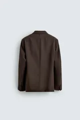 Blazer de corte regular fit confeccionado en tejido de lana, con cuello de solapas de muesca, manga larga con puños abotonados, bolsillos de vivo en el pecho y de plastrón en la cadera, cierre frontal de un botón y aberturas en la espalda.