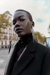 Abrigo de paño color beige con cuello solapa, manga larga con hombreras y cierre frontal con botones. Presenta bolsillos delanteros de doble vivo y abertura en la espalda.