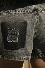 Short de jean gris oscuro con efecto degradé simulando los bolsillos y parche negro con logo bordado en el bolsillo trasero.