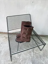 Botas de caña alta de gamuza marrón con puntera cuadrada, suela plana y tres tiras laterales con hebillas metálicas.