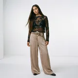 Blusa negra transparente de manga larga, con cuello redondo y detalles bordados y lentejuelas.