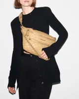 Riñonera negra capitoneada con tres cierres frontales, correa ajustable con hebilla y cadena metálica decorativa.