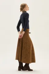 Falda midi acampanada de color camel, confeccionada en material con textura similar al cuero gamuzado.