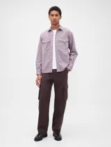 Camisa de jean de corte clásico en color azul oscuro, con cierre frontal de botones, cuello camisero y dos bolsillos frontales con solapa y botón.