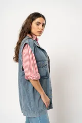 Chaleco oversize de jean celeste con cuello clásico, cierre frontal con botones metálicos, dos bolsillos con solapa en el pecho y corte a la cadera. Sin mangas.