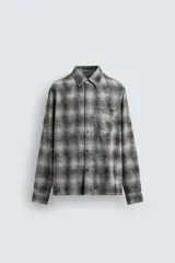 Camisa de corte relajado confeccionada en tejido de algodón con estampado de cuadros en tonos marrones y beige. Presenta cuello solapa, manga larga con puños abotonados, bolsillo plastrón en el pecho y cierre frontal con botones.