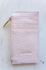 Tarjetero de cuero color rosa pálido con múltiples ranuras para tarjetas, cierre lateral con cremallera dorada y logo de la marca grabado en el frente.