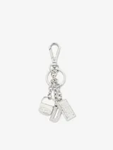Llavero metálico plateado con mosquetón y tres cadenas colgantes. Cuenta con tres charms distintivos de la marca: una miniatura del bolso 1DR, una placa con el logo de Diesel grabado y una letra 'D' decorada con incrustaciones de cristales.