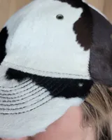Gorra tipo visera confeccionada en cuero con textura de pelo, diseño clásico con ojales metálicos de ventilación y ajuste posterior.