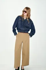 Chaqueta estilo bomber confeccionada en tejido denim azul oscuro. Presenta cuello solapa, cierre frontal con cremallera, mangas largas y bajo elástico. Incluye bolsillos delanteros de plastrón con solapa y botones.