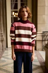 Buzo tejido de punto con diseño de rayas horizontales en tonos rosado, marrón y crema. Presenta cuello redondo alto y puños acanalados.