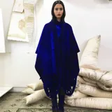 Capa azul de lana merino afieltrada, con guarda tejida en cuello y ruedo. Se puede usar como poncho o como capa abierta.