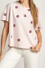 Remera rosa de algodón con estampado de lunares marrones.