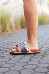 Sandalias bajas de cuero marrón con tres tiras: una de cuero marrón, una de cuero liso color visón y una de cuero con estampado animal print.