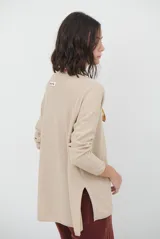 Sweater de tejido de punto color beige, con escote en V y mangas largas. Presenta un diseño básico y versátil de corte recto.