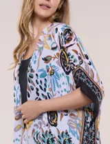 Kimono de gasa ligera con estampado floral en tonos marrones, amarillos y turquesas sobre base blanca, de corte amplio y abierto al frente, con mangas cortas tipo kimono y detalles de borlas en el ruedo asimétrico.