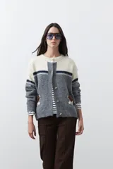 Cardigan de tejido jacquard con diseño de conejitos en los laterales, cuello redondo y cierre frontal con botones. Presenta un patrón de bloques de color en tonos beige y gris con detalles de rayas oscuras.
