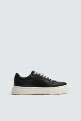 Zapatilla deportiva de estilo retro con parte superior de cuero sintético y suela de plataforma con diseño irregular y texturizado.