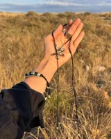 Collar tipo gargantilla con dije de flor metálica de acabado brillante, suspendido de un cordón doble de seda natural teñido a mano en color rojo.
