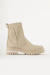 Bota tipo chelsea de caña media en color beige, con suela track dentada y paneles laterales elásticos acanalados.