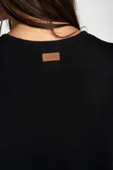 Vestido midi de punto negro con pequeño bordado de un velero en el pecho, mangas cortas y tajo lateral en el dobladillo.